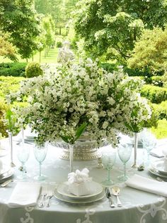 the table is set with white flowers and silverware