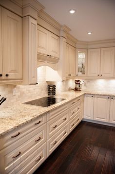 a kitchen with white cabinets and wood floors