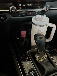 the interior of a car with an automatic coffee maker and cup holder on it's center console