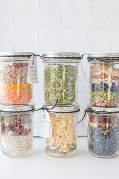 four glass jars filled with different types of food and labeled labels on each one side