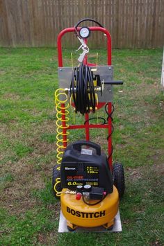 a yellow and black machine sitting on top of a grass covered field next to a fence