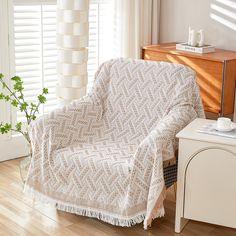 a living room with a white couch covered in a blanket next to a wooden table