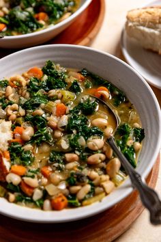 there is a bowl of soup with beans and spinach in it on the table