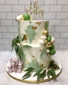 a three tiered cake with green and gold decorations on the top, along with an elephant figurine