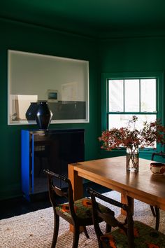 a dining room with green walls and wooden table