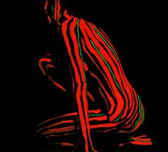 a red and green striped person sitting in the dark