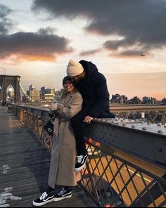 a man and woman standing on top of a bridge