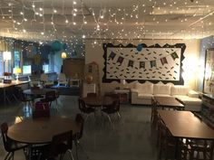 an empty room with tables and chairs, lights strung from the ceiling and decorations on the walls