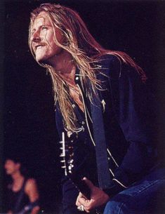 a man with long hair playing an electric guitar