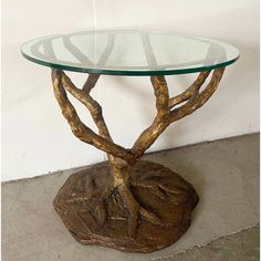 a glass table topped with a metal base and a tree branch design on top of it