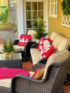 a patio with wicker furniture and potted plants on the side of the house