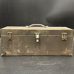 an old suitcase sitting on top of a gray table next to a black wall and floor