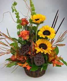 a basket filled with sunflowers and other flowers on top of a white table