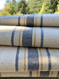 three blue and yellow striped towels are stacked on top of each other in front of some trees