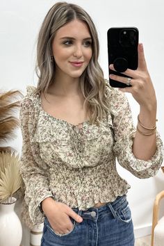 Flaunt a playful and stylish look with our "Mixed Florals" Top! This breezy square-neck blouse features a charming floral print, long flounce sleeves with ruffles, and delicate elastic details throughout. With a tie closure and keyhole at the center front neckline, it's the perfect blend of feminine and flirty. Get ready to turn heads and make a statement in this unique and quirky top! 100% Polyester Jaclyn is a size 1, wearing a small. Feminine Flowy Smocked Top With Floral Print, Flowy Smocked Top With Square Neck For Spring, Spring Square Neck Flowy Smocked Top, Flowy Square Neck Smocked Top For Spring, Feminine Fall Smocked Top With Floral Print, Feminine Floral Smocked Top For Fall, Feminine Ruffled Peasant Top With Square Neck, Spring Smocked Long Sleeve Top With Ruffle Hem, Spring Long Sleeve Smocked Top With Ruffle Hem