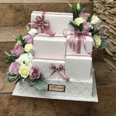 three white boxes with pink ribbons and flowers