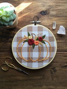 an embroidery hoop with flowers on it next to scissors