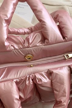 a pink handbag with gold hardwares on the handles and bottom part, sitting on a bed