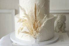 there is a white cake with feathers on the top and bottom, sitting on a table