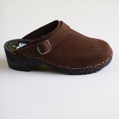 Clogs in brown suede leather with a classic strap over the ankle and a black wooden platform.  SIZE: EU 37 heel height - 4,5 cm / front platform - 3 cm  era: 2000s / y2k   content: suede leather, wood  condition: new without original box (new used) brand: Rega  Made in Poland Processing 1-2 business days.    - Fast free shipping via Global Express to the United States, Canada, Australia, Austria, Belgium, China, Czech Republic, Denmark, Estonia, Finland, Germany, Greece, Hungary, Ireland, Israel Brown Suede Closed Toe Mules, Suede Clogs With Wooden Heel And Round Toe, Classic Closed Toe Suede Clogs, Classic Suede Closed Toe Clogs, Brown Suede Mules With Wooden Heel, Leather Clogs With Suede Lining And Round Toe, Classic Suede Clogs With Buckle Closure, Brown Slip-on Clogs With Suede Lining, Suede Closed Toe Clogs With Buckle Closure