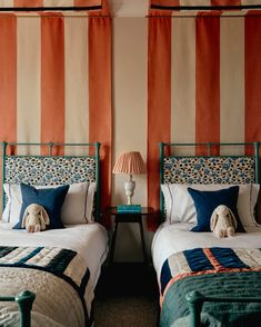 two beds in a room with orange and white striped walls