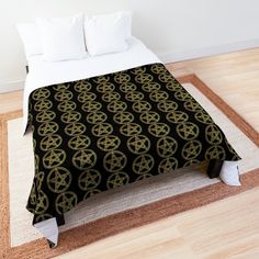 a bed with a black and gold blanket on top of it next to a white rug