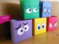 four colorful bags with eyes on them sitting on top of a wooden table in front of a wall