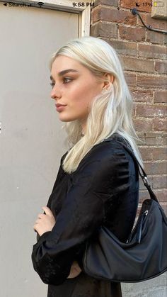 a woman with blonde hair is standing in front of a door and looking off to the side