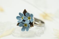 a ring with blue flowers sitting on top of some crystal rocks and petals in the background