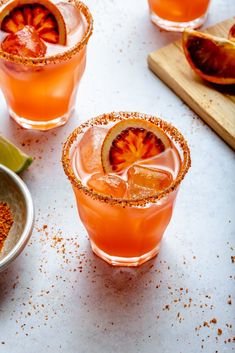 three glasses filled with blood orange margaritas and garnish