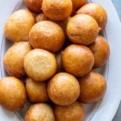 a white plate filled with fried pastries on top of a blue table cloth next to a knife and fork