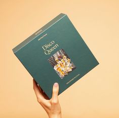 a person holding up a book in front of a tan background that says disco queen