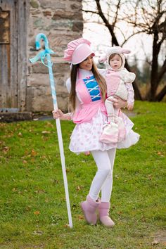 a woman holding a baby in her arms while standing next to a pole with a stuffed animal on it