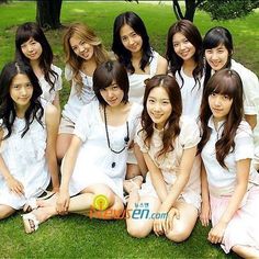 a group of young women sitting next to each other on top of a grass covered field