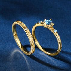 two gold wedding rings with blue topaz and diamond accents, on a blue background