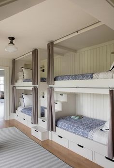 bunk beds are lined up against the wall in this room with curtains on both sides