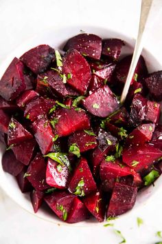 a white bowl filled with cooked beets and parsley