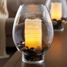 a glass vase filled with rocks on top of a wooden table next to a candle