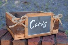 a wooden box sitting on top of bricks with a chalkboard saying cards attached to it