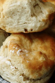 two biscuits stacked on top of each other in front of a plate full of rolls