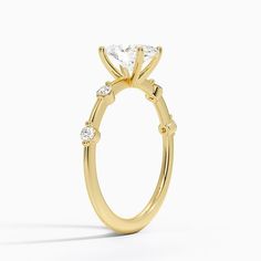 a yellow gold engagement ring with three stones on the side and a center stone in the middle