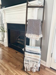 an old ladder is used as a blanket rack in front of a fire place and fireplace