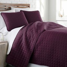 a bed with purple bedspread and pillows