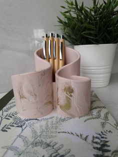 a set of four pink marbled utensils and spoons on a table next to a potted plant