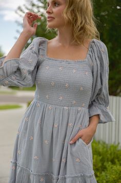 This stunning puff sleeve midi dress features a smocked bodice, embroidered flowers, tiered skirt and pockets for an ultra-feminine look. The puff sleeve midi dress is perfect for any special occasion. This dress pairs comfort and style for a standout look that will earn you compliments. steel blue embroidered florals smocked top square neckline lined pockets midi maxi length true to size Self: 100% cotton / Lining: 100% polyester hand wash cold model is wearing a small. Height is 5'5" Spring Smock Dress With Square Neck, Summer Dress With Balloon Sleeves And Smocked Cuffs, Spring Dress With Smocked Cuffs And Square Neck, Spring Smocked Dress With Square Neck And Smocked Cuffs, Spring Puff Sleeve Dress With Smocked Balloon Cuffs, Spring Smocked Dress With Square Neck And Gathered Sleeves, Spring Midi-length Smocked Dress With Elastic Sleeves, Spring Midi Dress With Ruffles And Balloon Sleeves, Feminine Smock Dress With Puff Sleeves