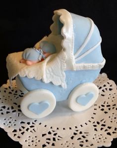 a blue and white baby carriage cake sitting on top of a doily