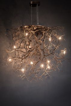 a chandelier made out of branches with lights hanging from the top and bottom