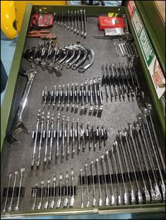 there are many wrenches and other tools in the box on the table, including screwdrivers