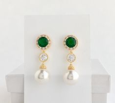 I've created this classic cubic zirconia and pearl bridal jewelry set in gold plated brass setting and the set includes: # Earrings feature large 12mm Swarovski pearls that dangle from brilliant cut green emerald cubic zirconia with halo setting 12mm ear stud and round connector. Halo setting gives a brilliantly beautiful effect. Total length of the earrings is 3.8 cms. #Classic pearl bridal necklace and pendant set with gold plated brass peg and bail. Necklace features a pendant with large 12mm Green Gold-plated Bridal Earrings For Wedding, Green Gold Plated Bridal Earrings For Wedding, Green Pearl Earrings, Gold Bridesmaid Jewelry, Bridal Jewelry Pearl Sets, Pink Pearl Earrings, Bridesmaid Pearl Earrings, Pearl Earrings Gold, Gold Bridal Necklace