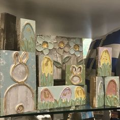 several wooden blocks with paintings on them in a store display case, some are painted and others are made out of wood